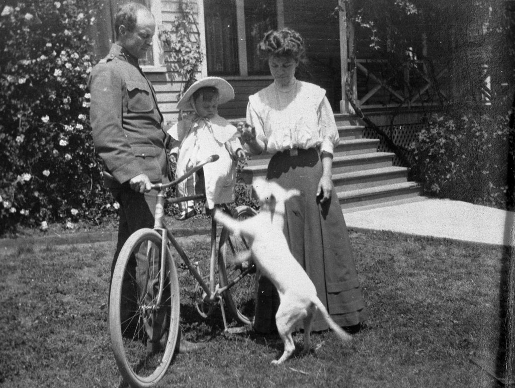 Captain Edwin C. Long, wife Georgene, and their son, Edwin, Jr., with their dog and bicycle on the lawn of their Funston Avenue quarters.