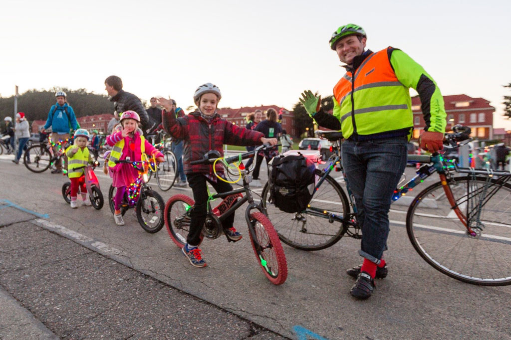 Children on bicycles with adults waving