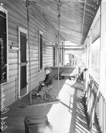 A child takes a ride on the front porch of the servicemen's quarters.