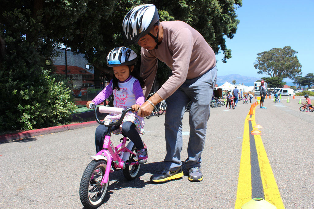 Man helping little girl ride a bike