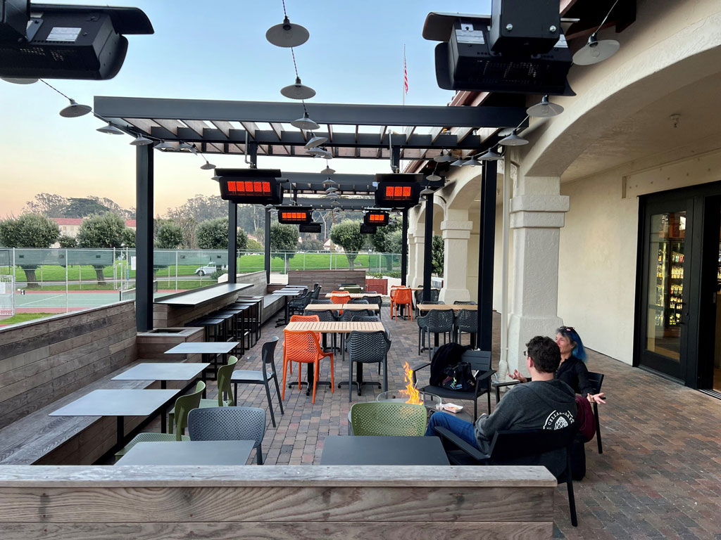 A couple visitors sitting around fire pit at outdoor patio at Presidio Bowl