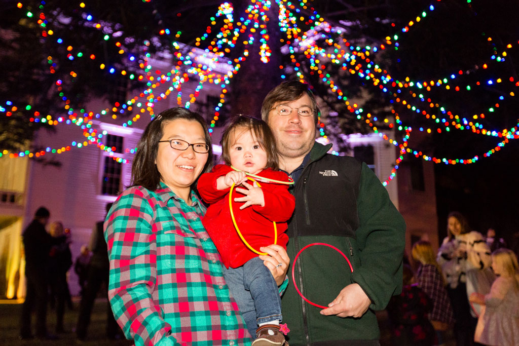 Parents and baby in front of tree with lights