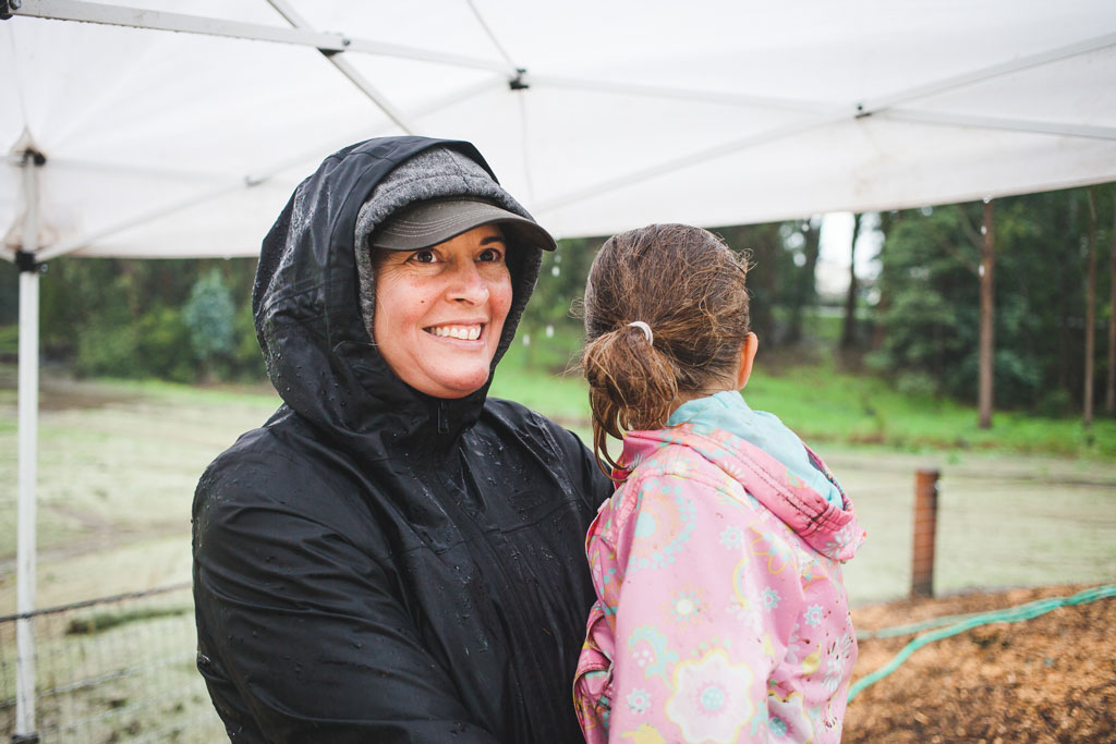 Woman carrying young girl in rain jackets