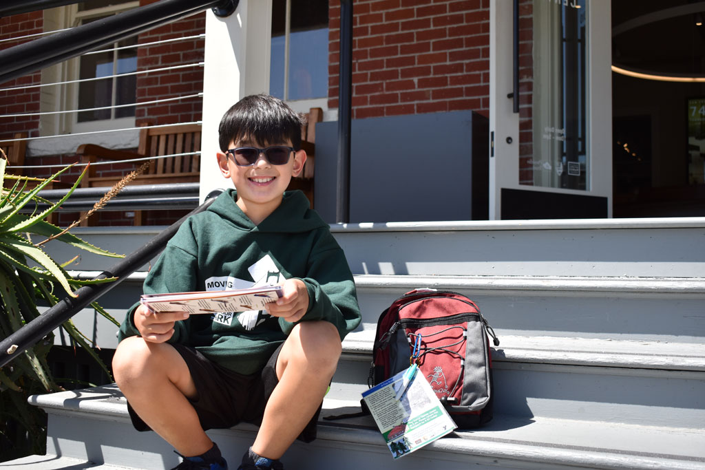 Fisher Tomlinson sitting on Presidio Visitor Center stairs next to the Presidio Explorer Backpack