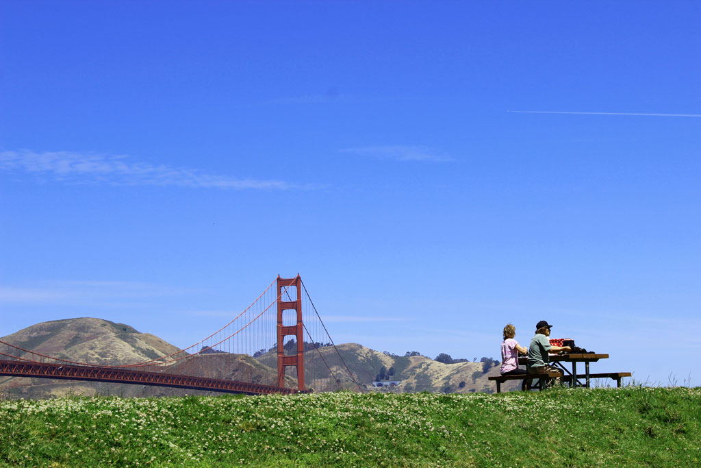 A couple picnickers at picnic table at West Bluff with Golden Gate Bridge views