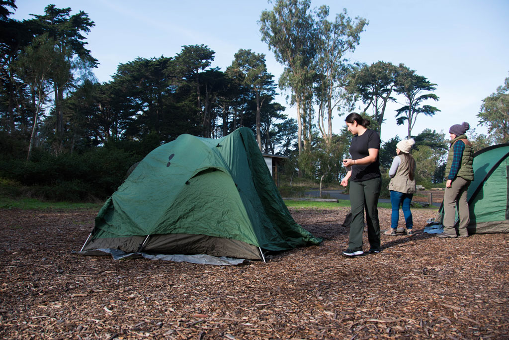 A few people pitching green tents at Rob Hill