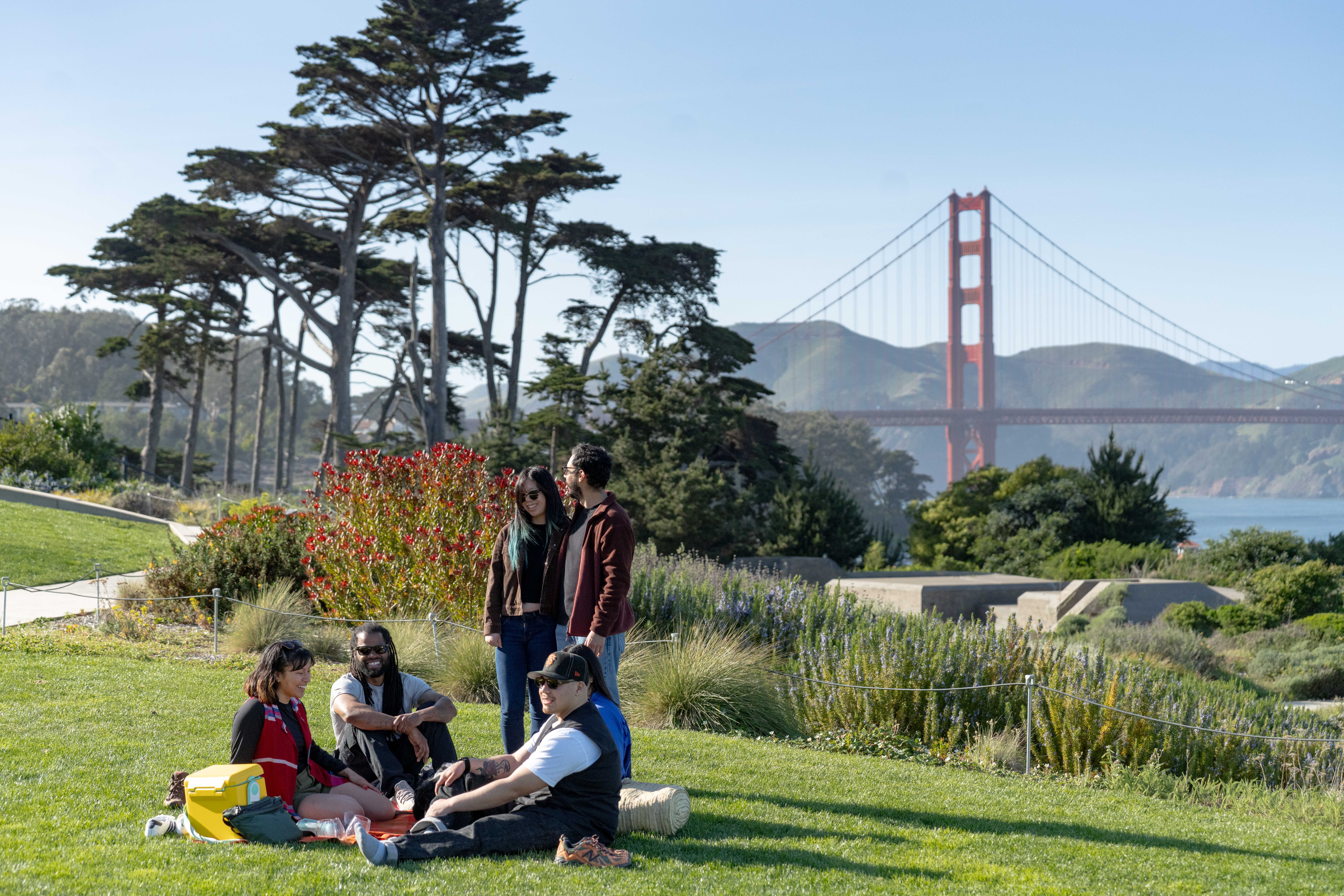 A group of adults having a picnic at Battery Bluffs with the Golden Gate Bridge in the background