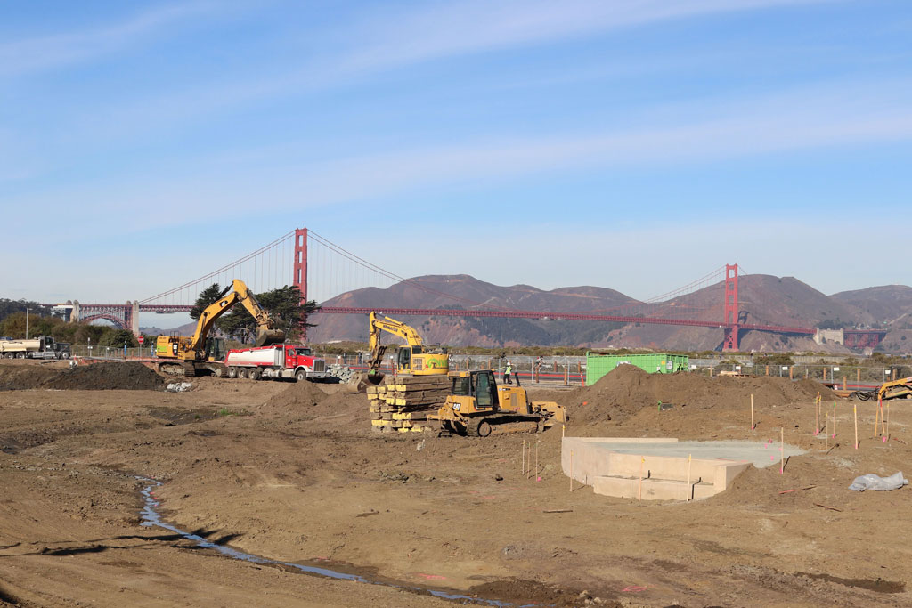 Construction vehicles on site with Golden Gate Bridge in the background