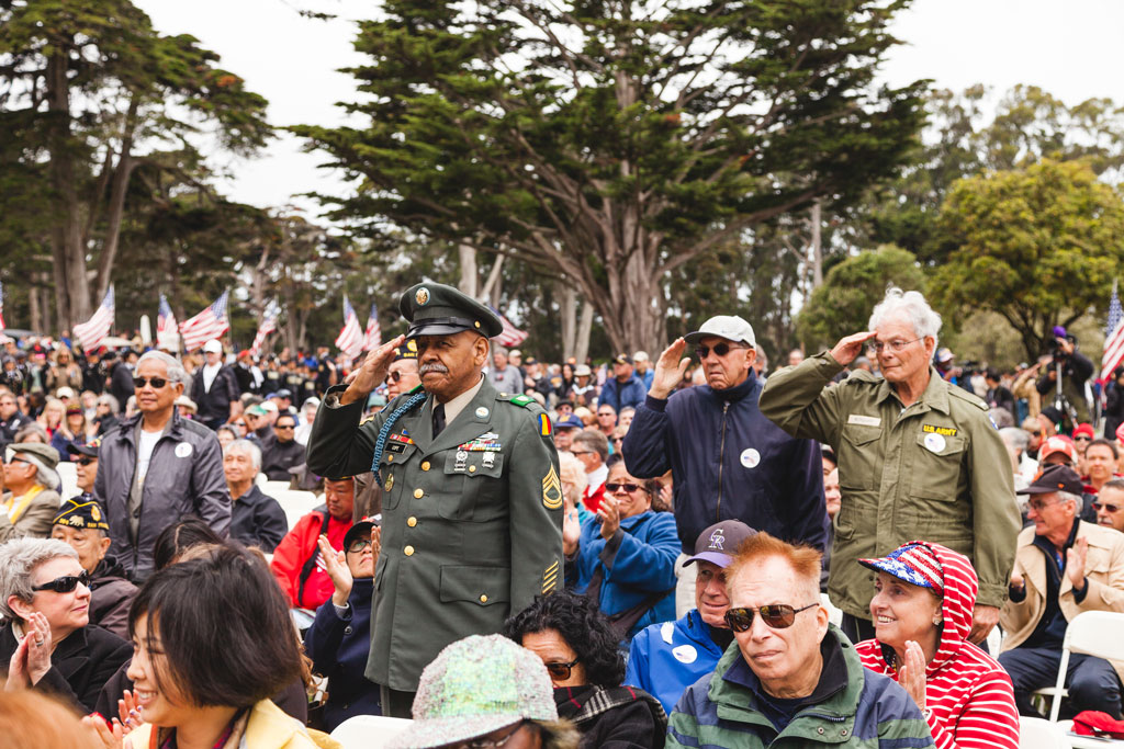 A few people saluting in the Memorial Day Commemoration audience