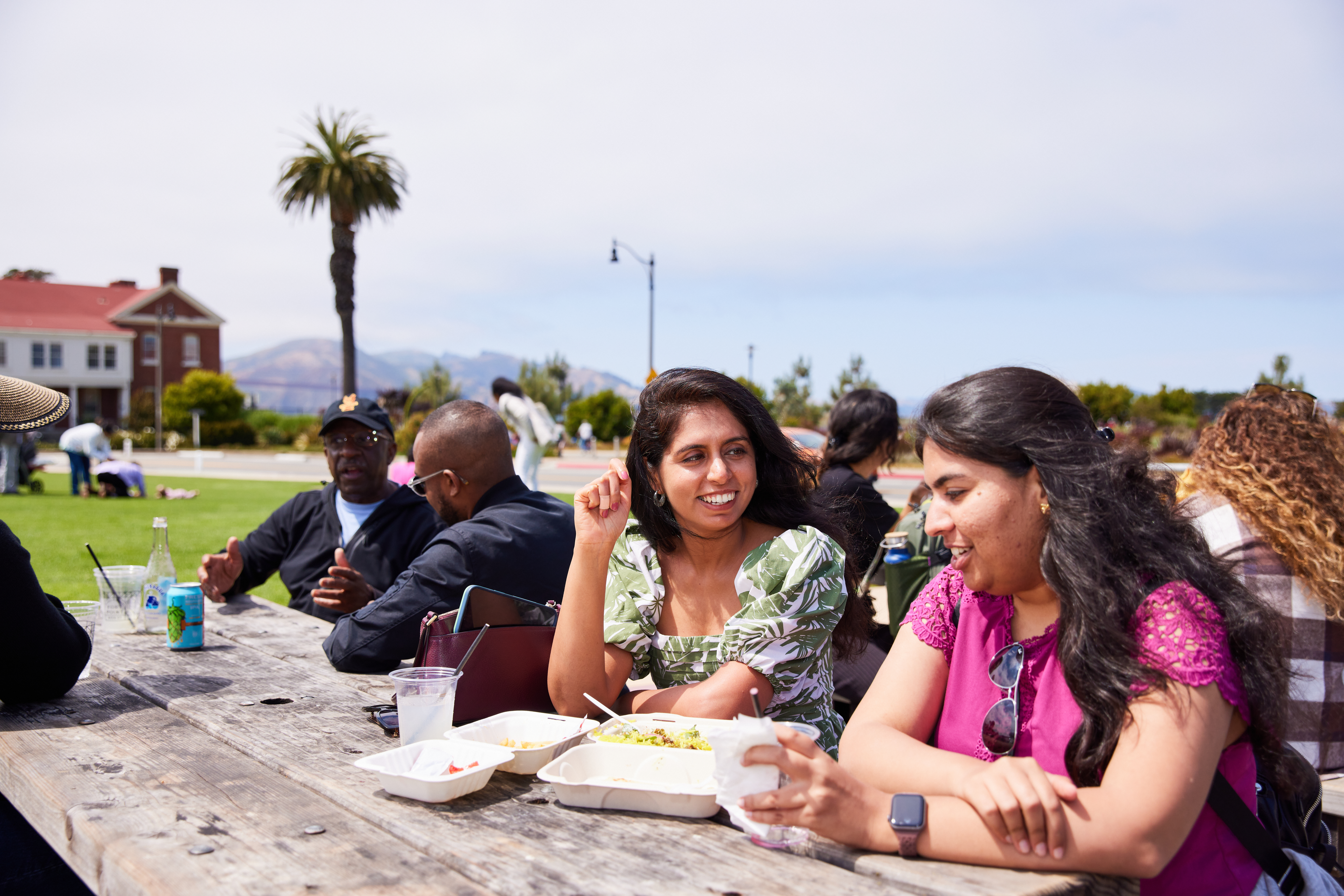 two women sitting at picnic table eating food on the main parade lawn