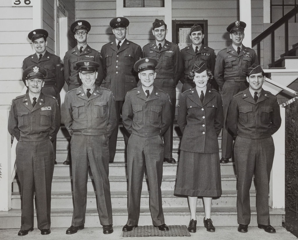 Eleven members of the 6002 Area Service Unit in uniform posing on steps of a Presidio building