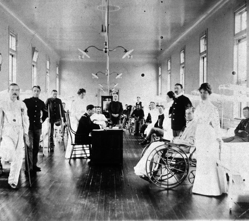 Patients in crutches and wheelchairs, nurses, doctors posing for photograph