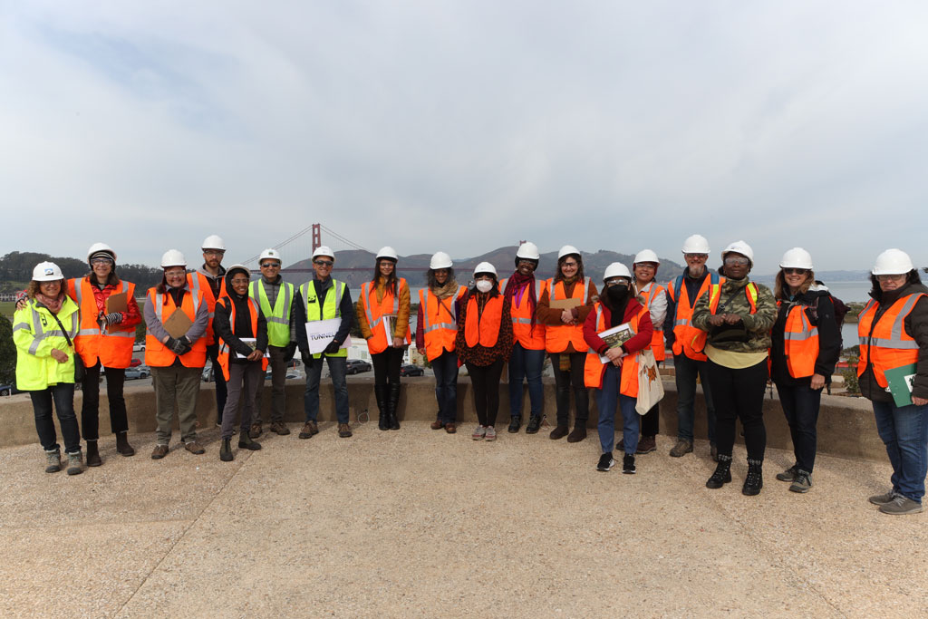 Group in safety vests and helmets with Golden Gate Bridge in the background