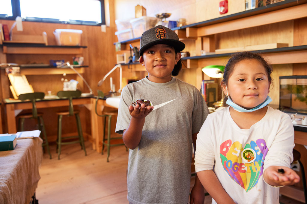 Boy and girl with items on hands in Field Station