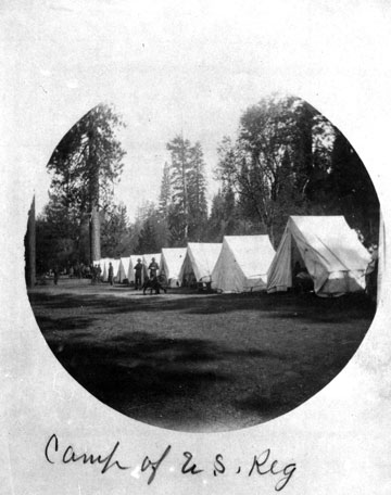 Soldiers in front of lined tents at camp