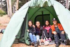 Four children in a tent at Rob Hill Campground in the Presidio of San Francisco.