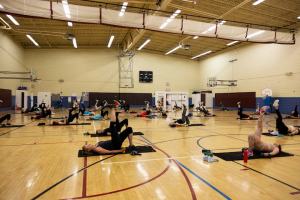 Many people stretching in a class in the gym of the Presidio Y. Photo courtesy of the Presidio Y.