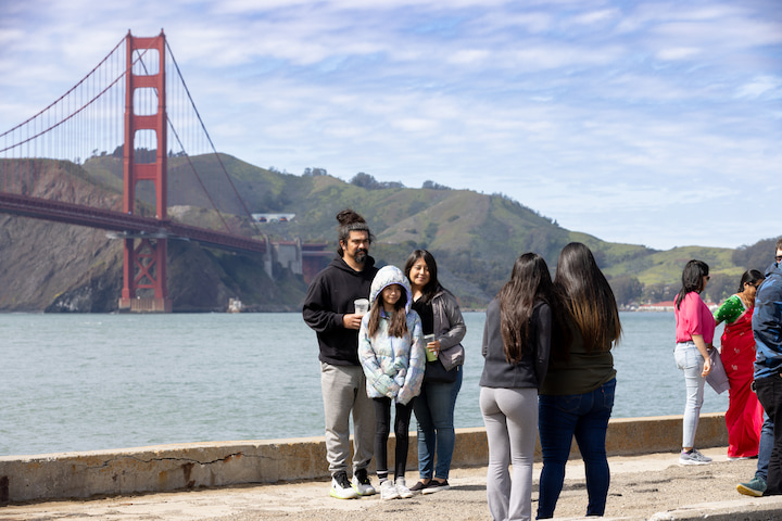 A family taking a photo at Torpedo Wharf with the Golden Gate Bridge in the background.