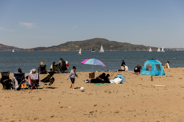 Beachgoers on the sand at East Beach in the Presidio, with Alcatraz in the background.