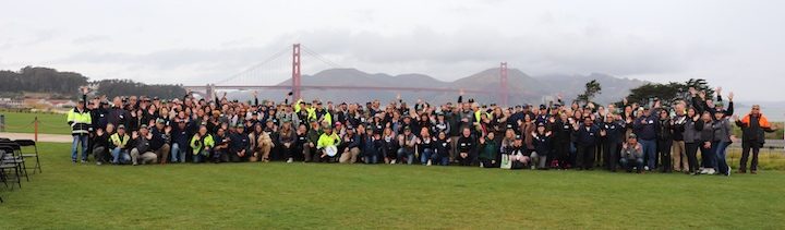 A group shot of Presidio Trust staff on a lawn with the Golden Gate Bridge in the background.