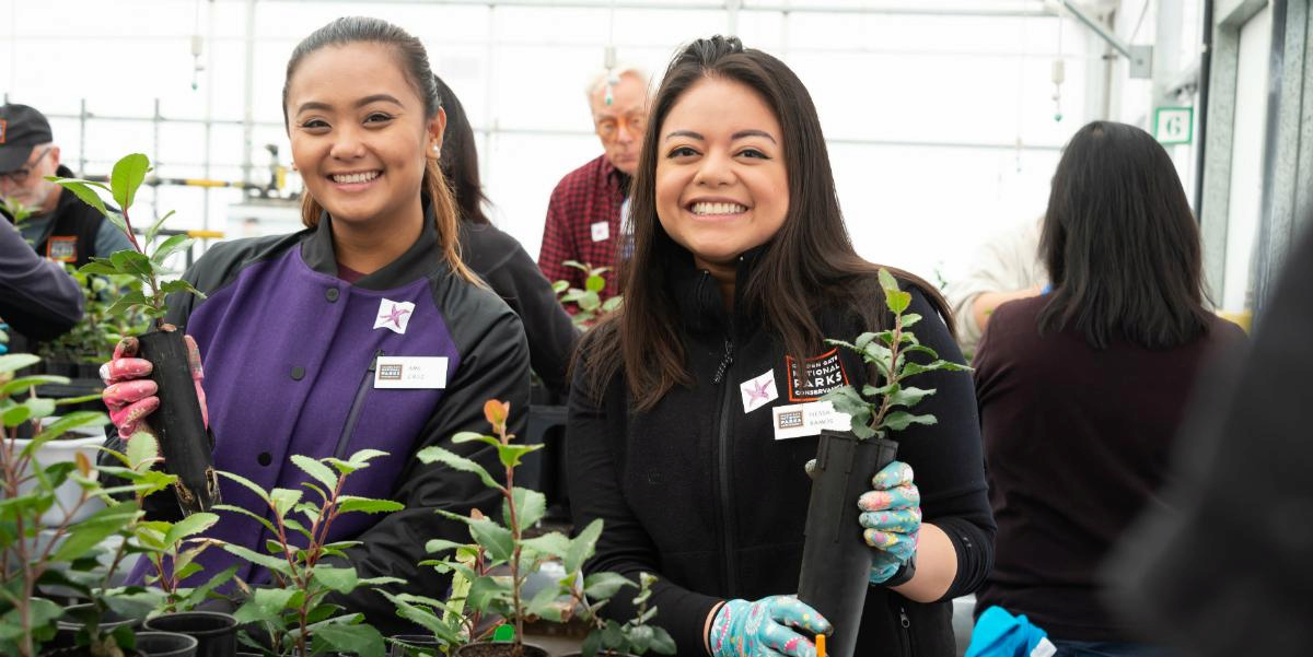 Two women in the nursery holding plants.