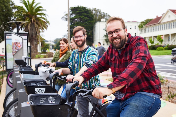 Two men and two women rent Bay Wheels bikes in the Presidio.