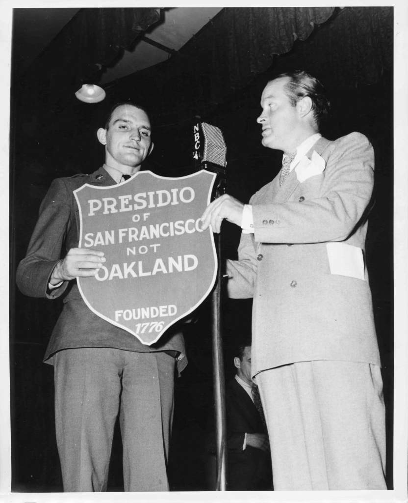 Private Charles Heinrichs presents Bob Hope with a plaque.