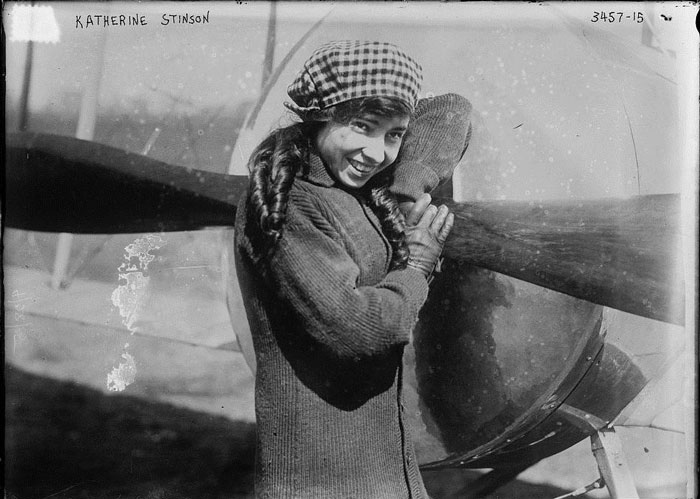 Black and white photograph of Katherin Stinson leaning on the wing of her plane.