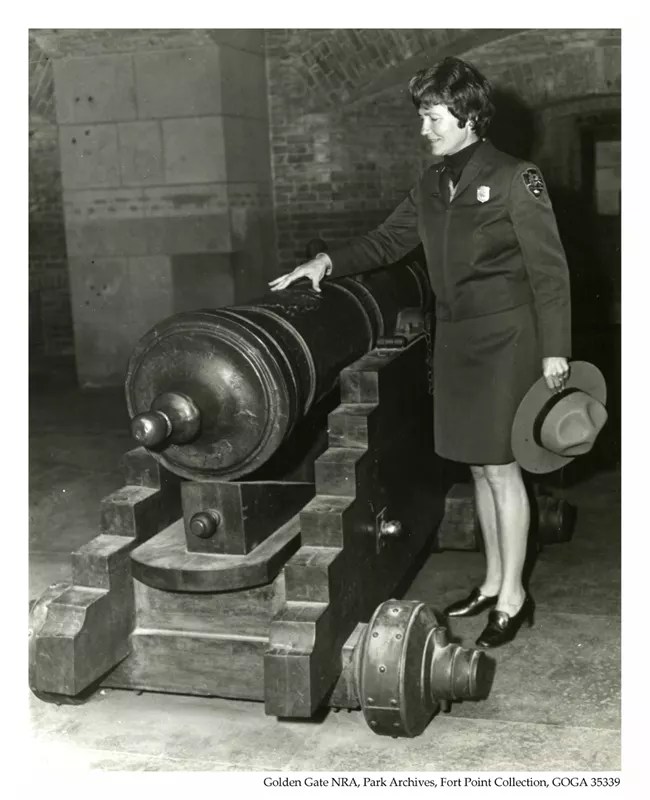 Black and white image of Marjorie M. "Mike” Hackett inspecting a canon.