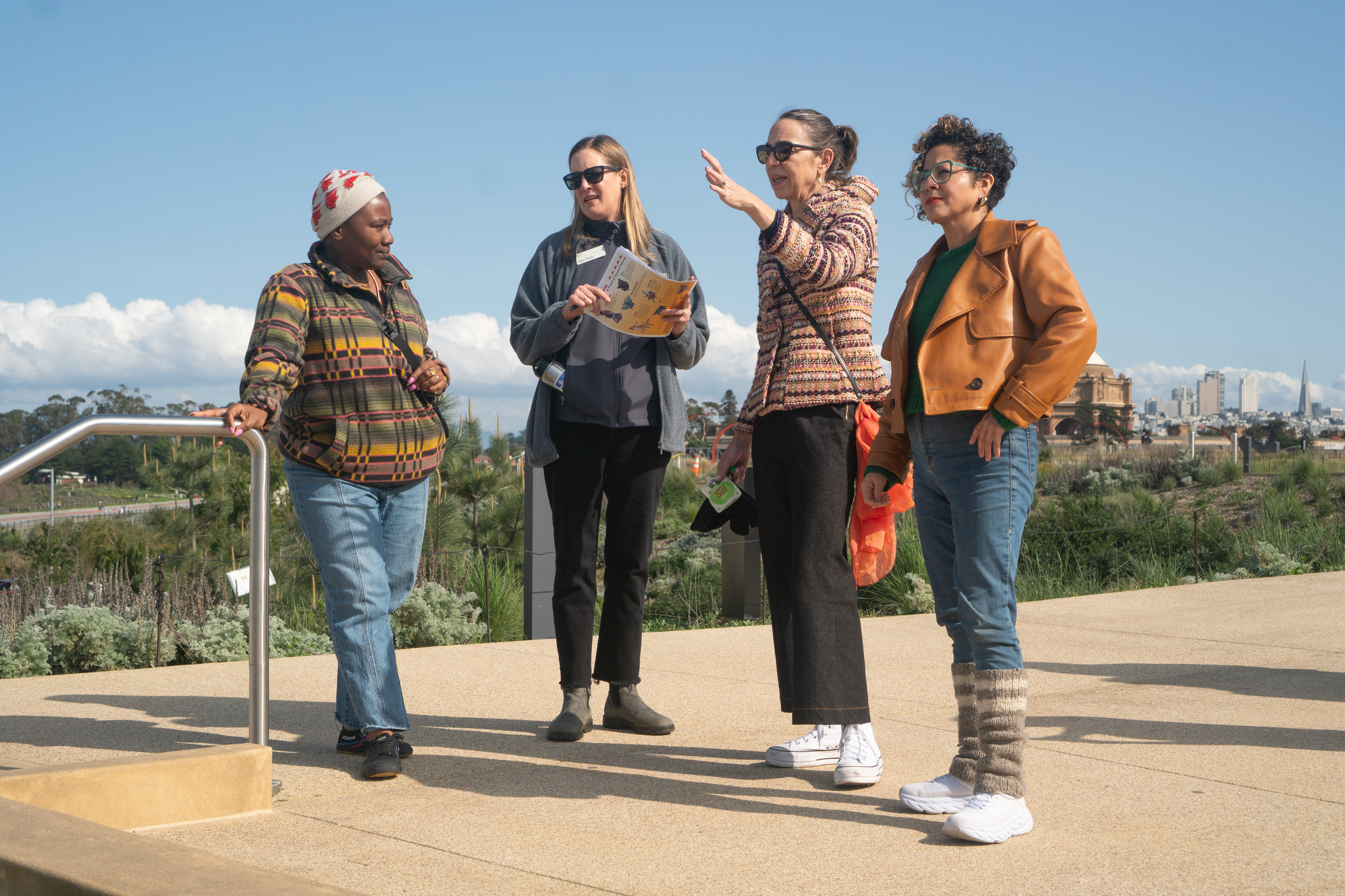 A group of women, Tosha with Favianna and representatives from the Presidio’s Community Partnership team, standing on the Presidio Tunnel Tops deep in discussion.
