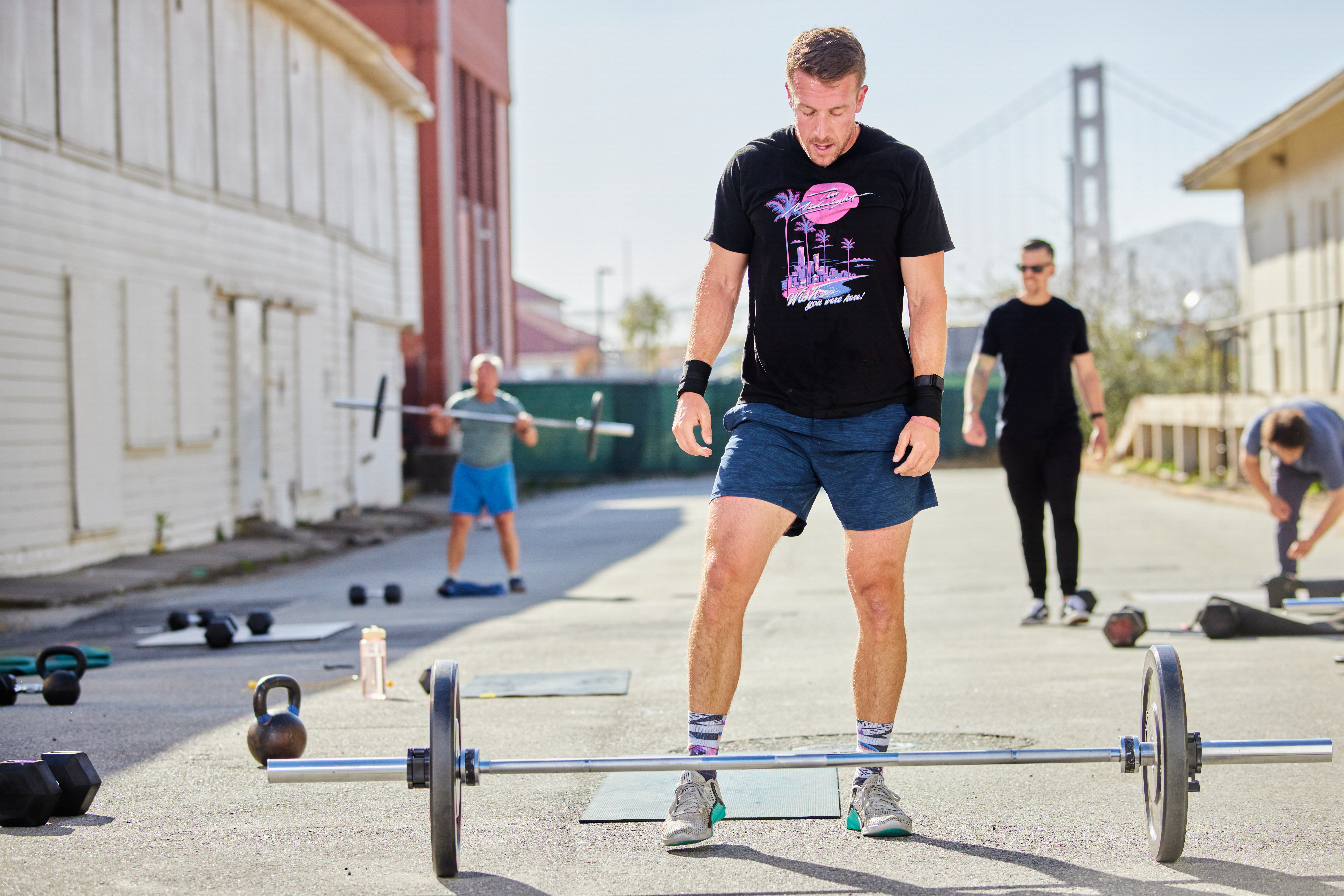 Man working out with a weighted bar with the golden gate bridge in the background
