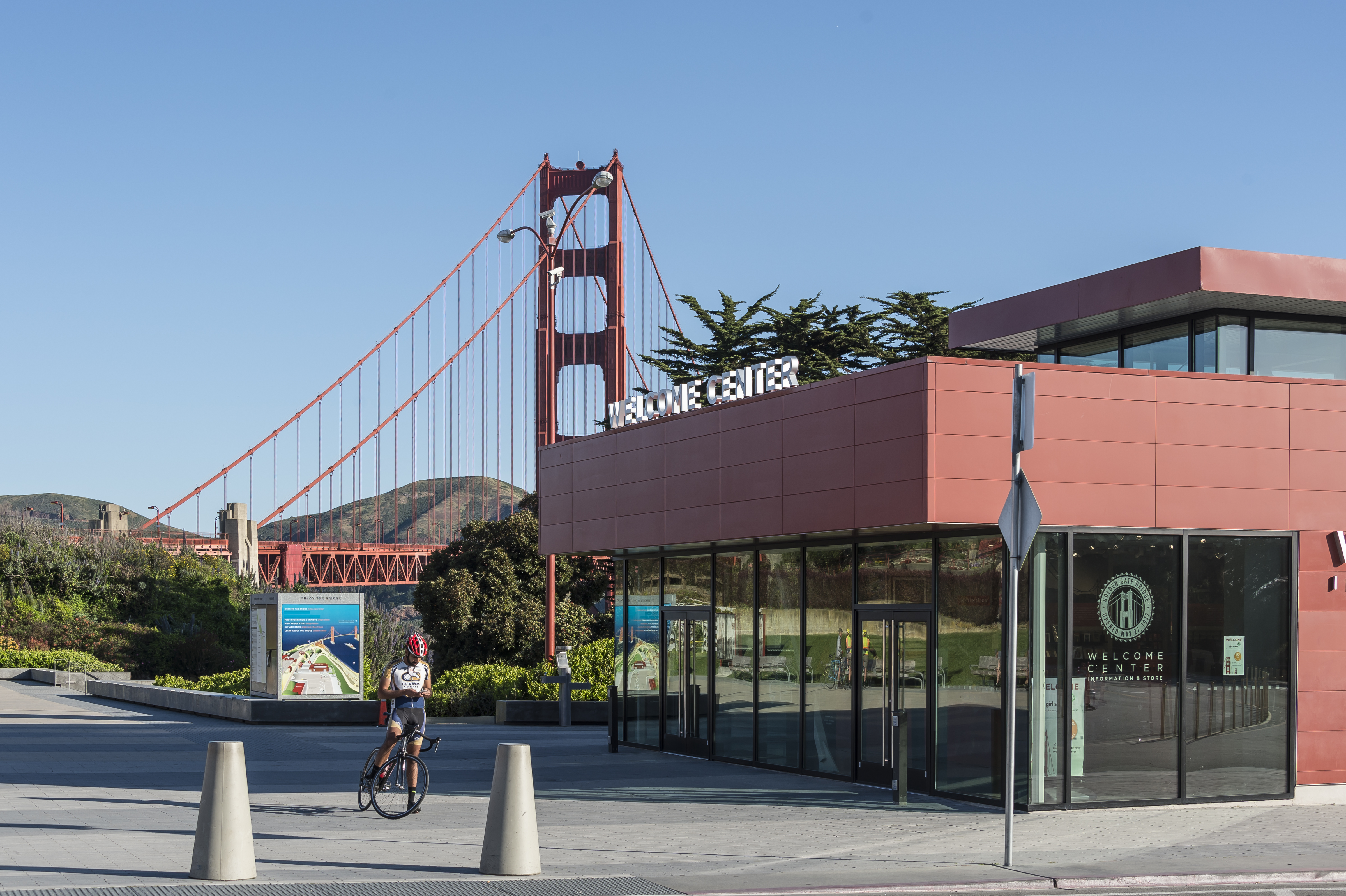 Biker paused outside of the Golden Gate Bridge Welcome Center with the Golden Gate Bridge in the background