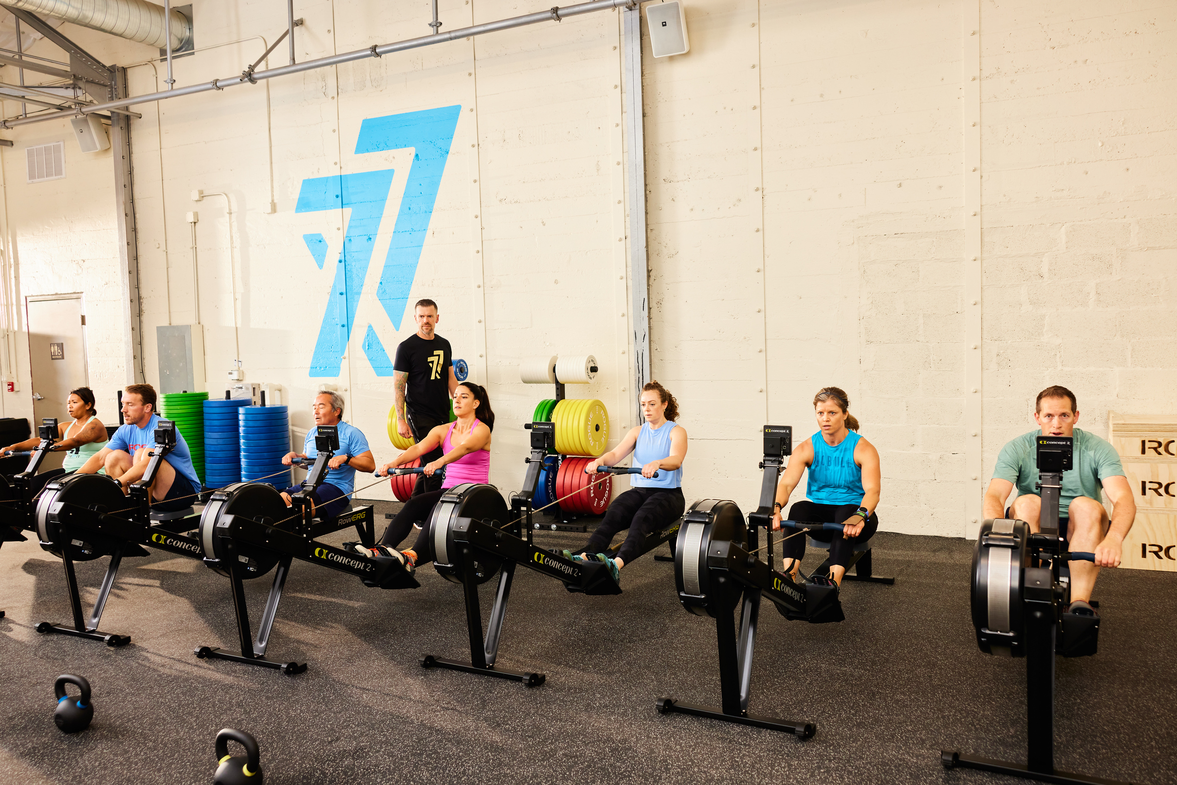 Group of people working out on a rowing machine in a workout room