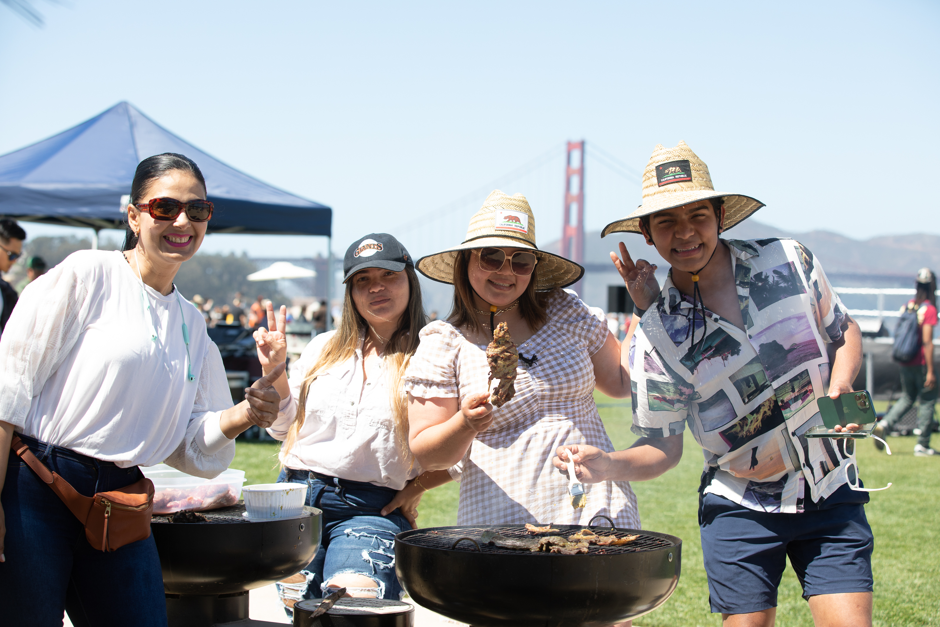 Four people grilling at Presidio Tunnel Tops with the golden gate bridge in the background