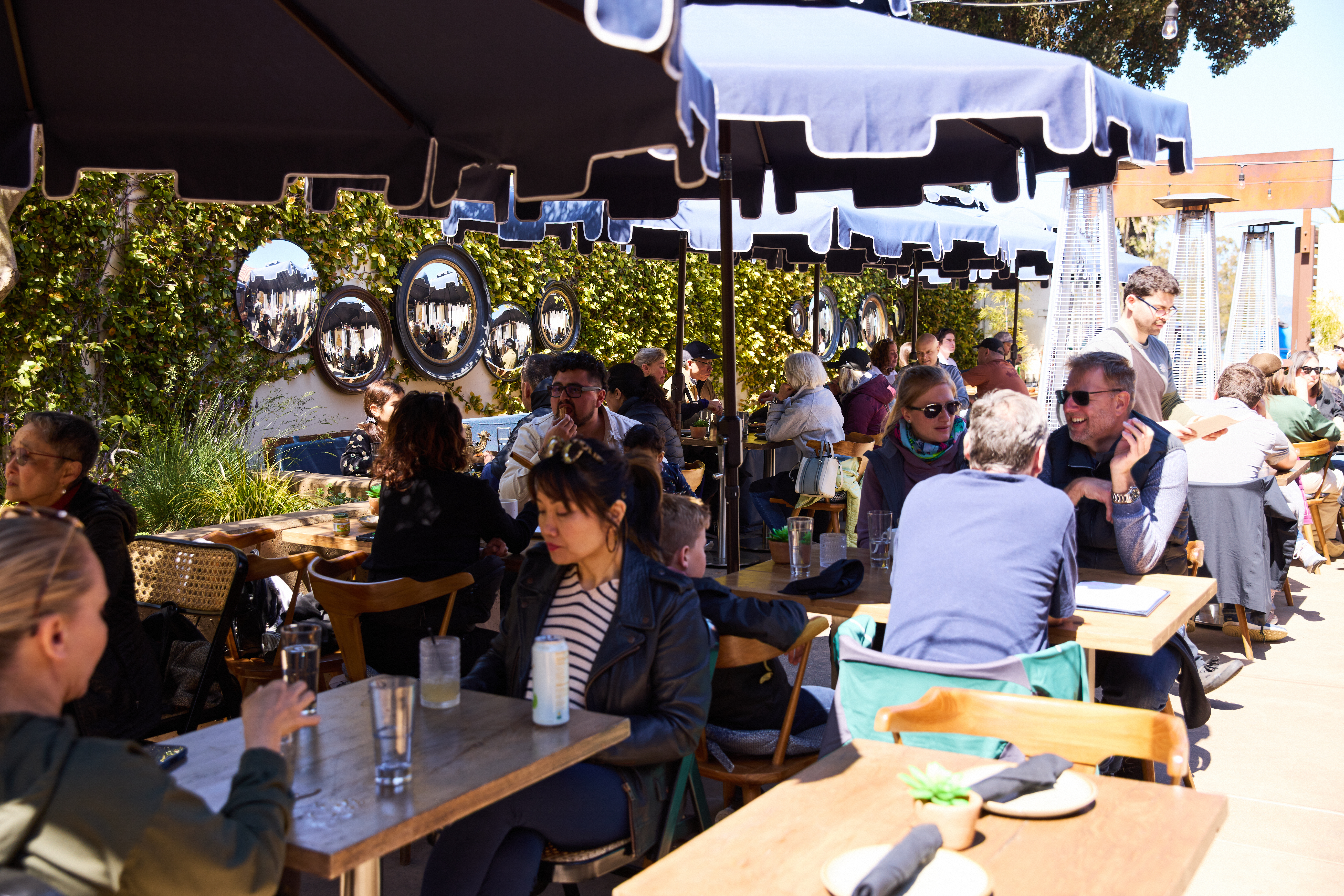 visitors sitting outside on patio under umbrella eating