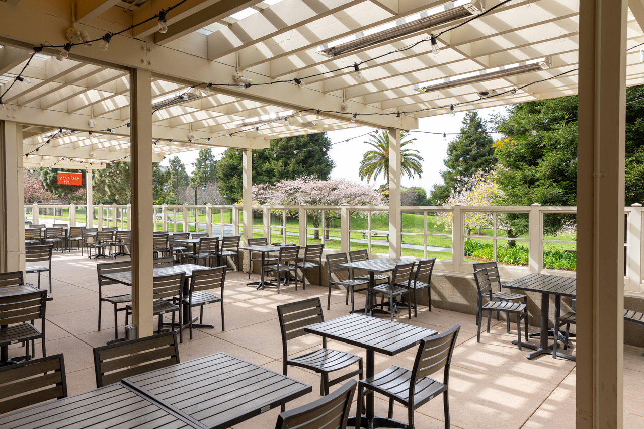 Piccino Presidio patio with tables and chairs outside and Letterman park in the background