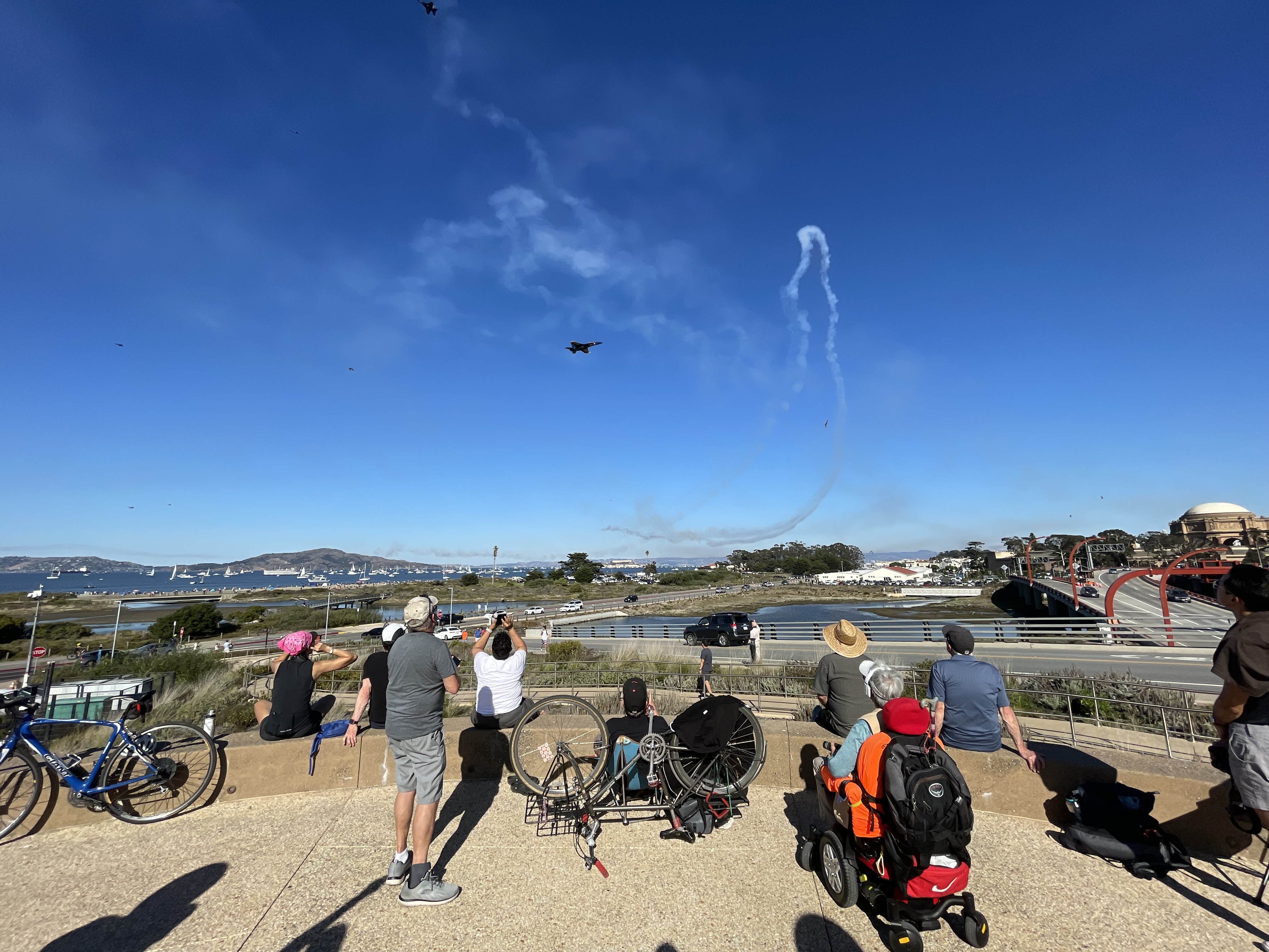 large group of people standing on presidio tunnel tops with sail boats in the background and blue angels in the air looking east
