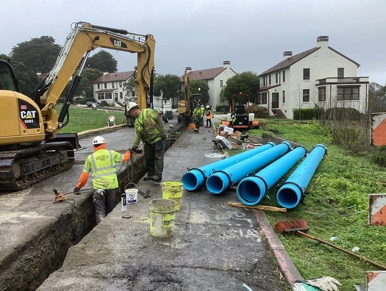 blue pipes being laid inside street with construction workers